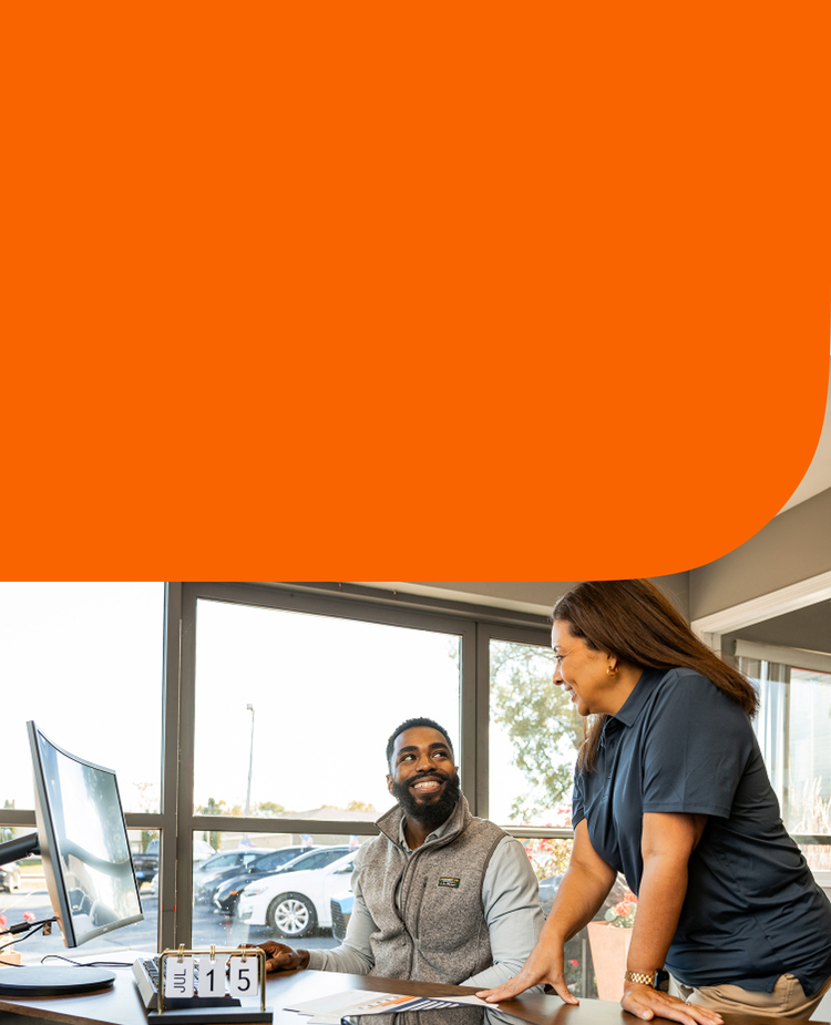 Man and woman at a desk inside a car dealership